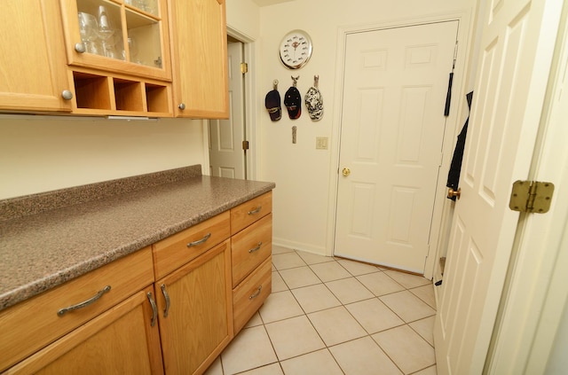 kitchen with open shelves, dark countertops, light tile patterned flooring, and glass insert cabinets