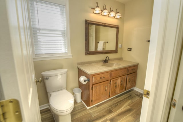 bathroom with wood finish floors, baseboards, toilet, and vanity