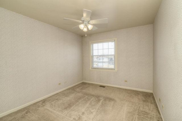 carpeted empty room with visible vents, wallpapered walls, baseboards, and a ceiling fan