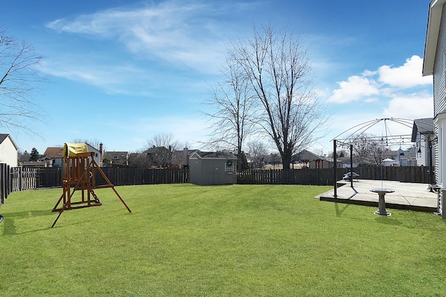 view of yard featuring a patio, a playground, a fenced backyard, and an outdoor structure