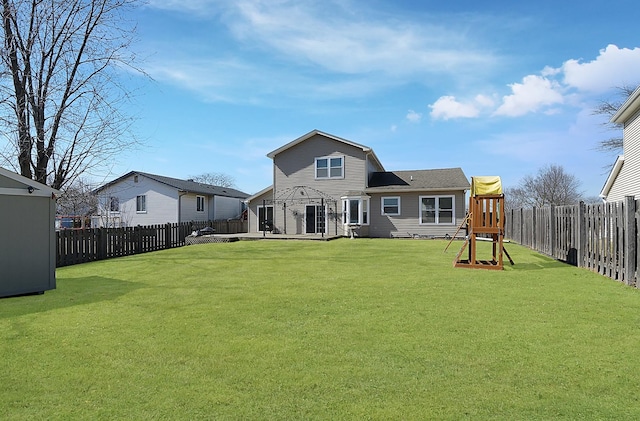 rear view of house featuring a lawn, a fenced backyard, and a playground