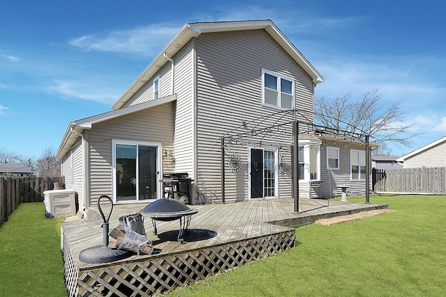 rear view of property featuring a deck, a yard, and a fenced backyard