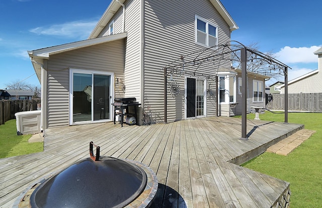 wooden terrace with a lawn, area for grilling, and a fenced backyard