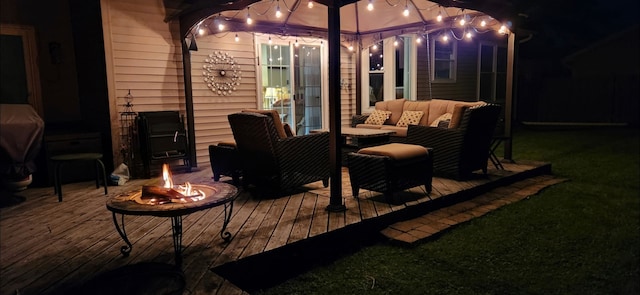 patio at twilight featuring an outdoor living space with a fire pit and a wooden deck