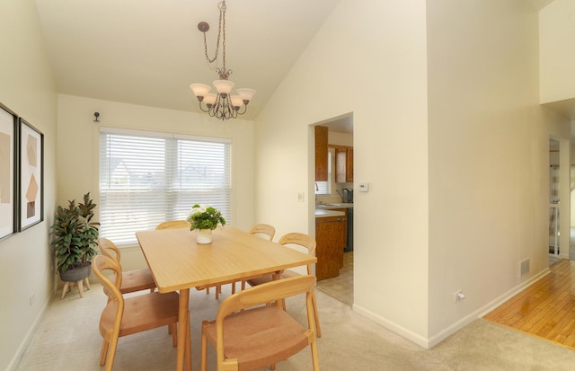 dining space featuring visible vents, baseboards, light colored carpet, an inviting chandelier, and high vaulted ceiling