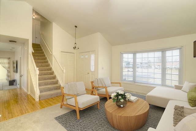 living area featuring stairs, lofted ceiling, wood finished floors, and baseboards