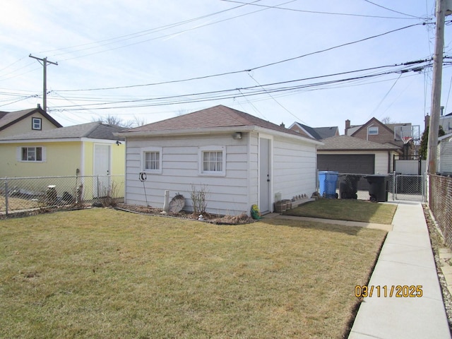 rear view of property featuring a yard, an outdoor structure, and a fenced backyard