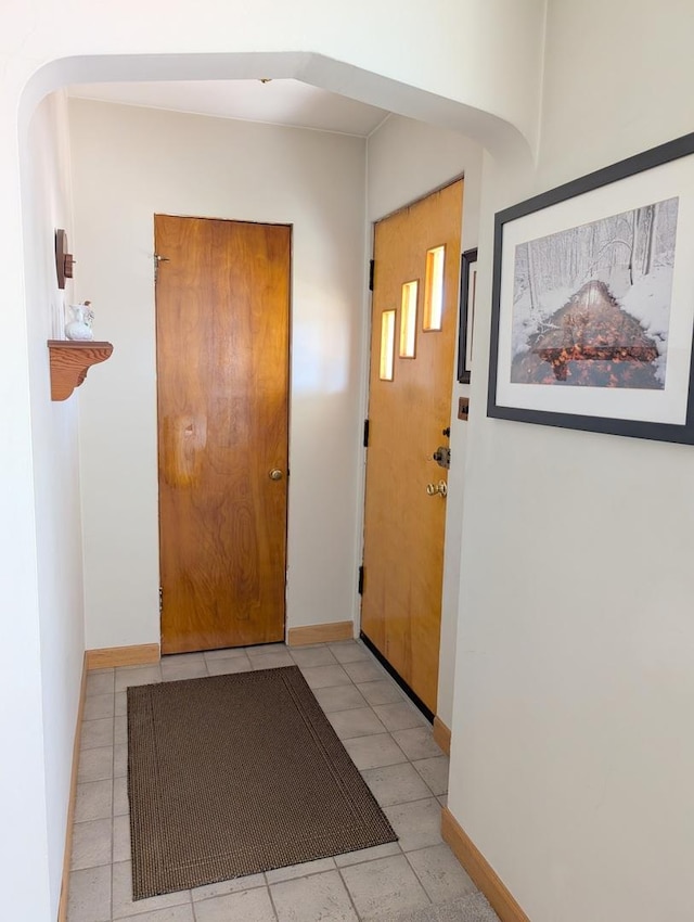 foyer featuring baseboards and arched walkways