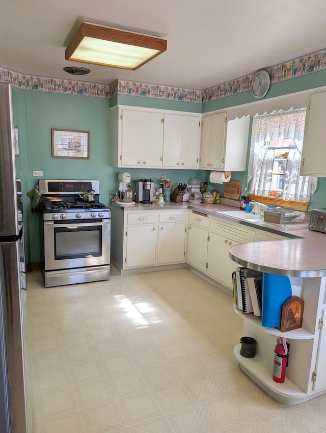 kitchen featuring a sink, stainless steel appliances, white cabinets, light countertops, and light floors