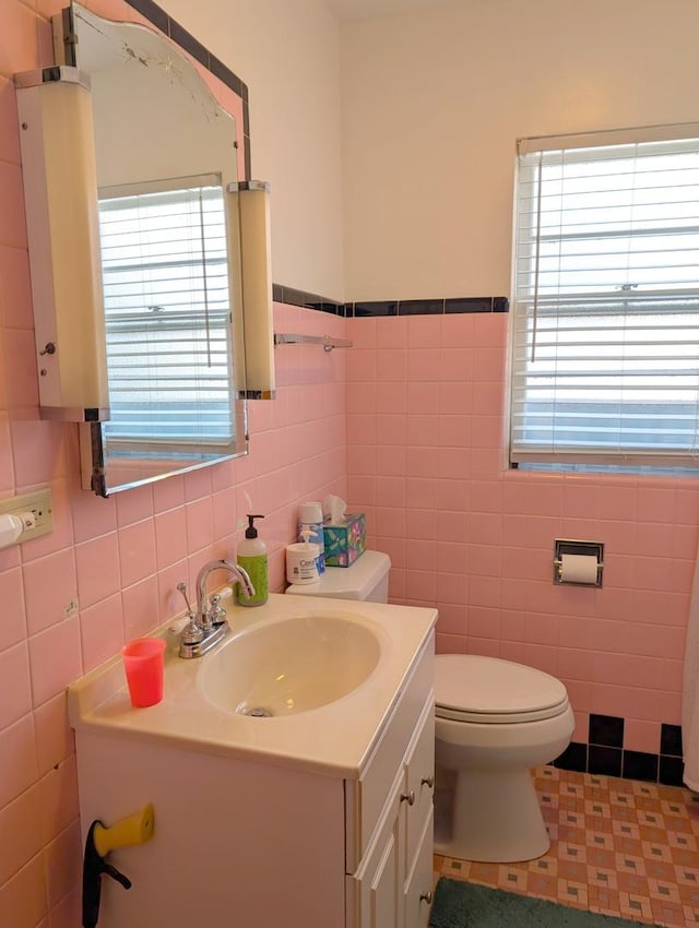 bathroom featuring plenty of natural light, toilet, tile walls, and vanity