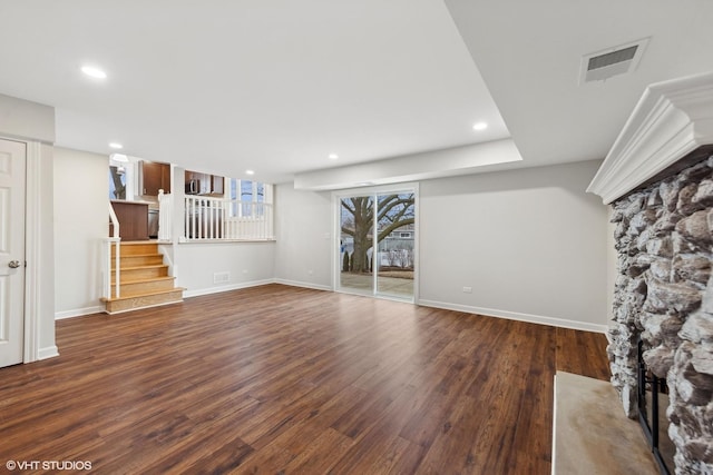 unfurnished living room with stairway, baseboards, visible vents, and dark wood-style flooring