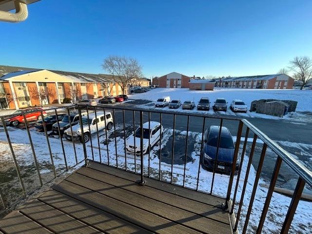 snow covered back of property featuring a residential view