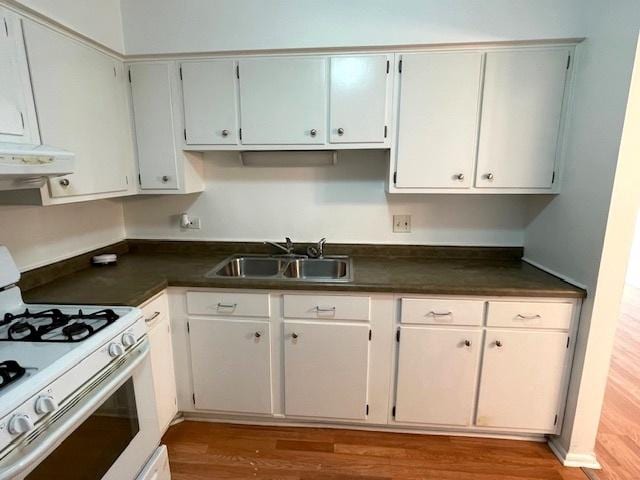 kitchen featuring white gas stove, a sink, dark countertops, wood finished floors, and ventilation hood