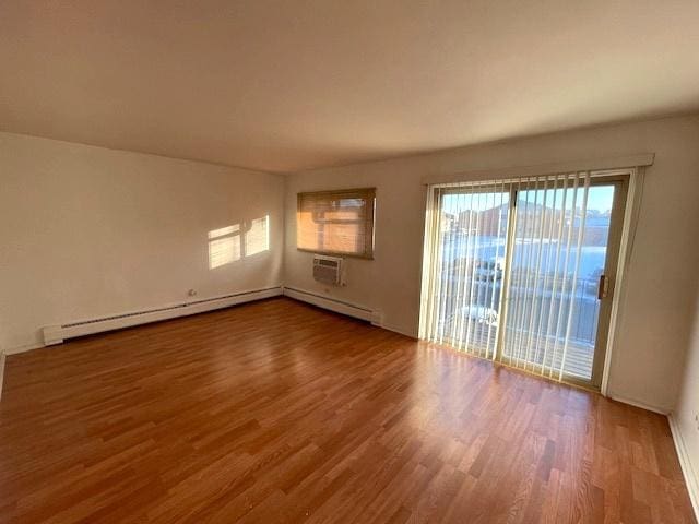 spare room featuring baseboard heating and wood finished floors