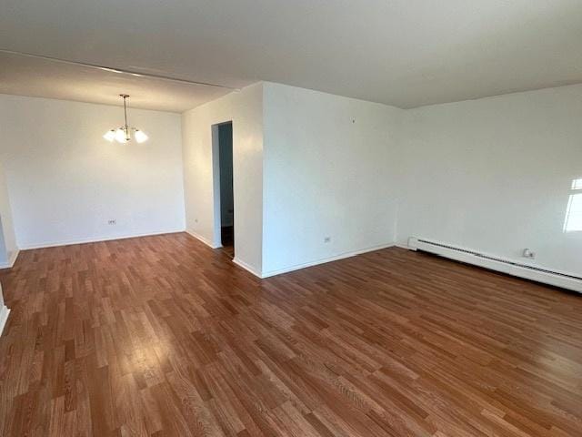 unfurnished room featuring baseboards, a notable chandelier, baseboard heating, and wood finished floors