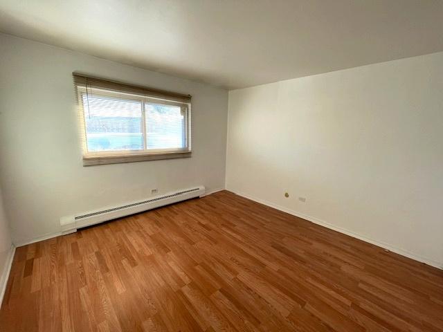 spare room featuring baseboard heating and wood finished floors