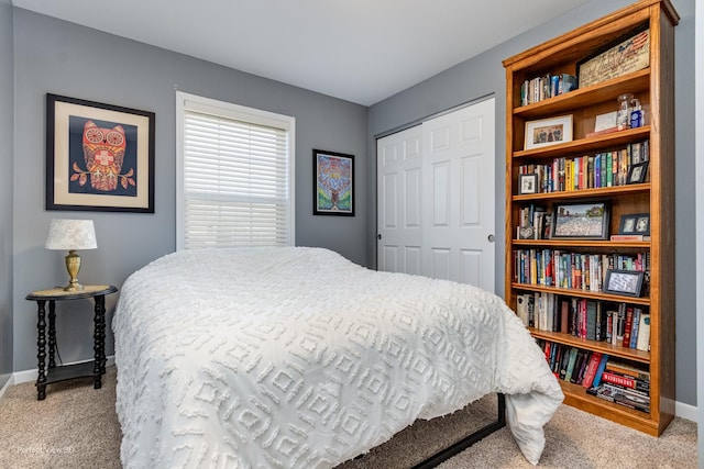 carpeted bedroom with a closet and baseboards