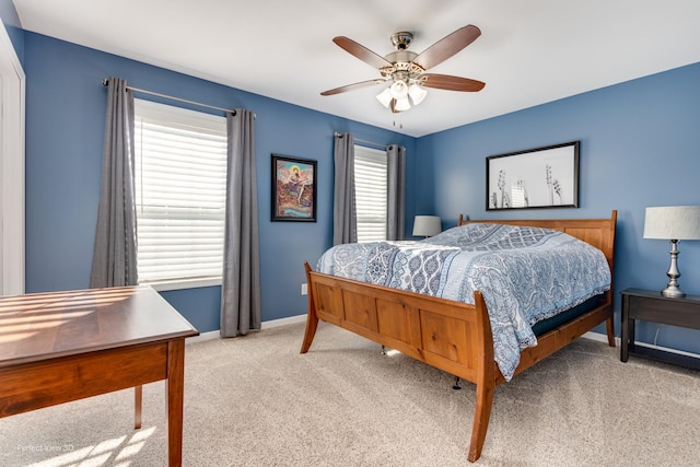 bedroom featuring light colored carpet, a ceiling fan, and baseboards