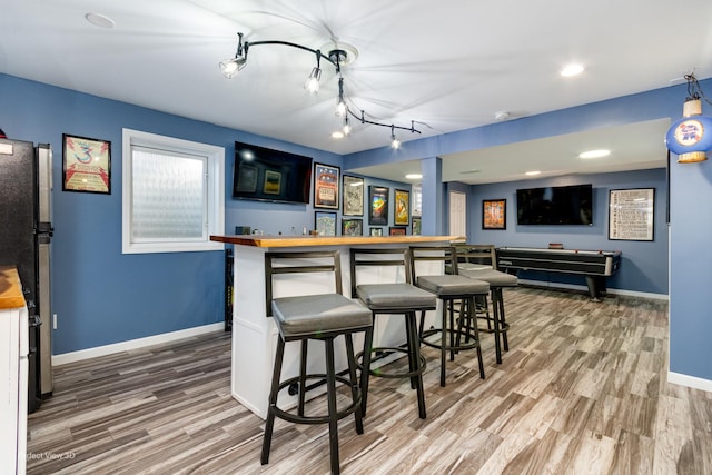 bar with wood finished floors, freestanding refrigerator, recessed lighting, baseboards, and a dry bar