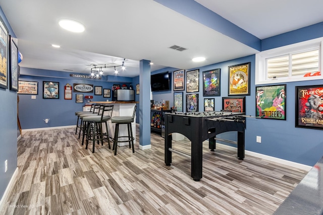 playroom with visible vents, wood finished floors, baseboards, and a dry bar