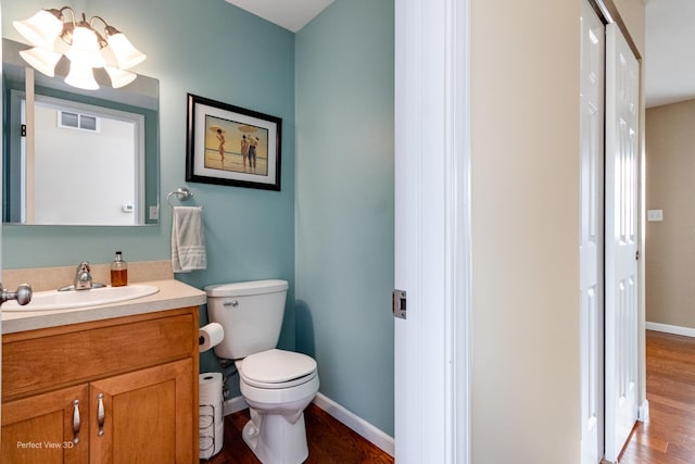 bathroom with visible vents, baseboards, toilet, wood finished floors, and vanity