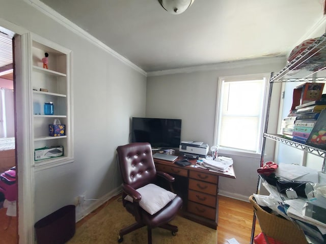 office space featuring crown molding, light wood-style flooring, built in shelves, and baseboards