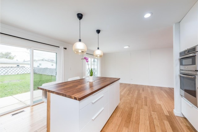 kitchen with visible vents, wooden counters, modern cabinets, and white cabinetry