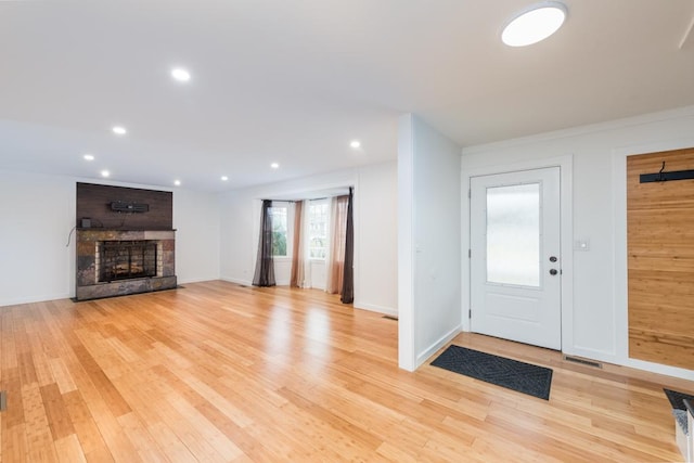 foyer featuring visible vents, baseboards, recessed lighting, a brick fireplace, and light wood-type flooring