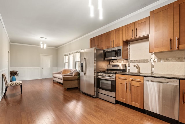 kitchen featuring a sink, dark countertops, a wainscoted wall, and stainless steel appliances