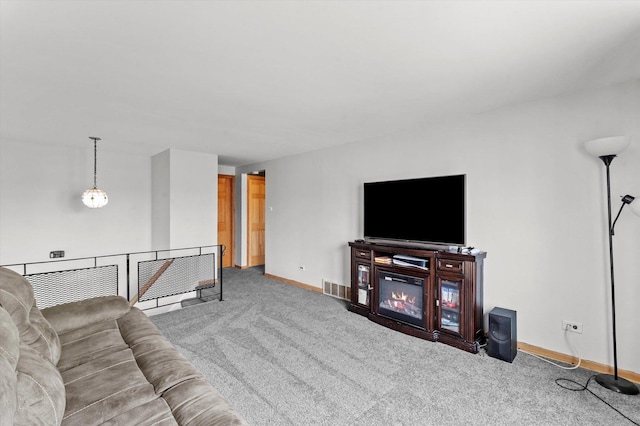 carpeted living room with a glass covered fireplace, visible vents, and baseboards