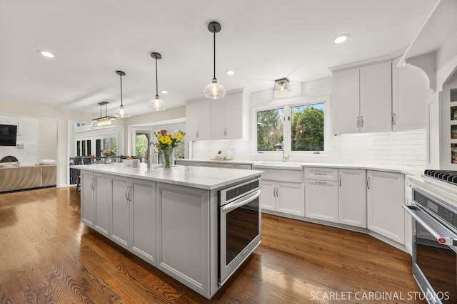 kitchen with a healthy amount of sunlight, decorative backsplash, and stainless steel oven