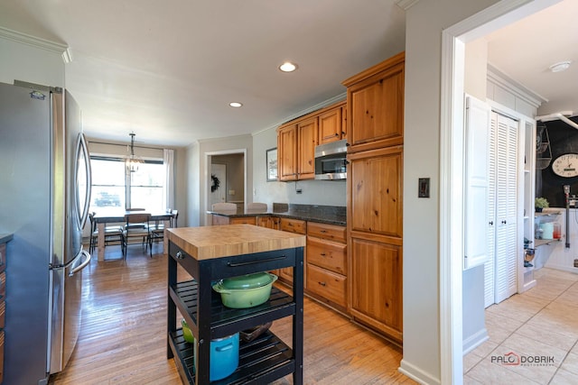 kitchen with light wood-type flooring, ornamental molding, recessed lighting, appliances with stainless steel finishes, and brown cabinetry