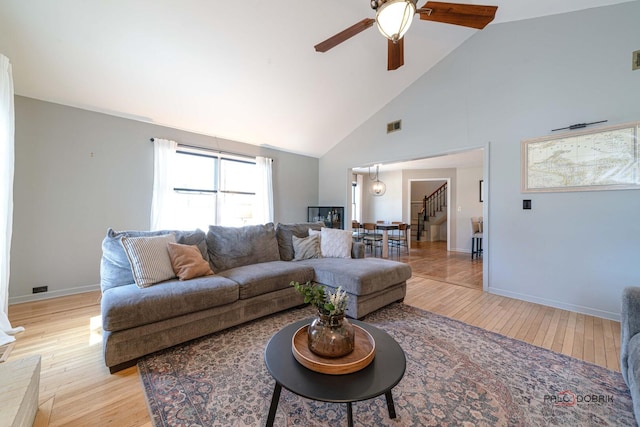 living area featuring light wood finished floors, visible vents, stairs, and ceiling fan