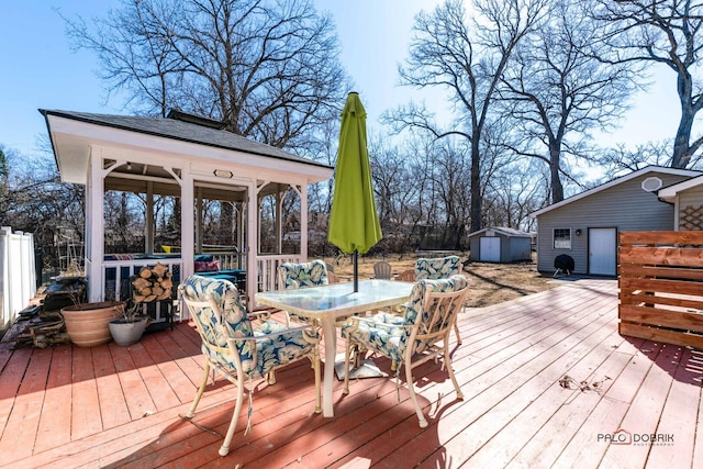 deck featuring an outbuilding, outdoor dining space, a storage shed, and fence