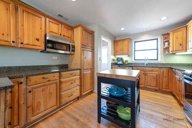 kitchen with light wood finished floors, visible vents, crown molding, stainless steel appliances, and open shelves