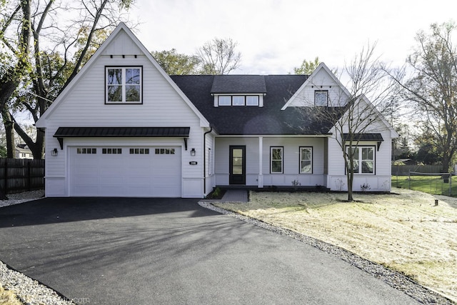 modern farmhouse featuring a standing seam roof, aphalt driveway, fence, and metal roof