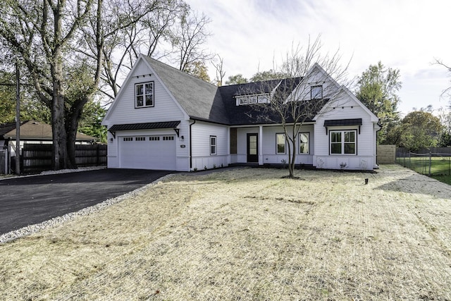 view of front of home featuring aphalt driveway, an attached garage, and fence