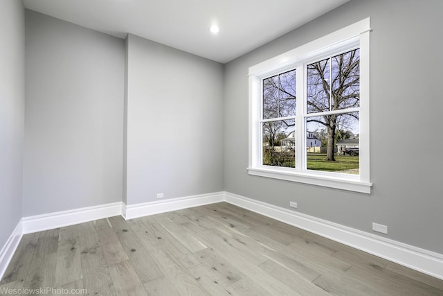 unfurnished room featuring plenty of natural light, baseboards, and light wood finished floors