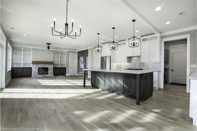 kitchen featuring tasteful backsplash, a fireplace, freestanding refrigerator, light wood-style floors, and white cabinets