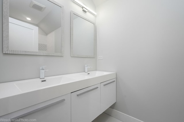 bathroom with double vanity, baseboards, visible vents, and a sink