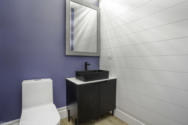 half bath featuring toilet, wood finished floors, and vanity