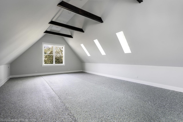 additional living space featuring baseboards and vaulted ceiling with beams