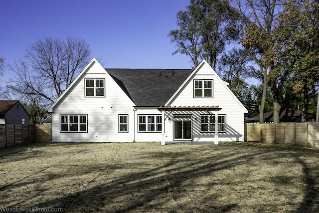 back of house with board and batten siding, a fenced backyard, and a pergola