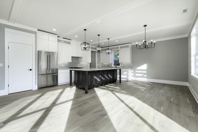 kitchen featuring visible vents, light wood finished floors, freestanding refrigerator, decorative backsplash, and white cabinetry