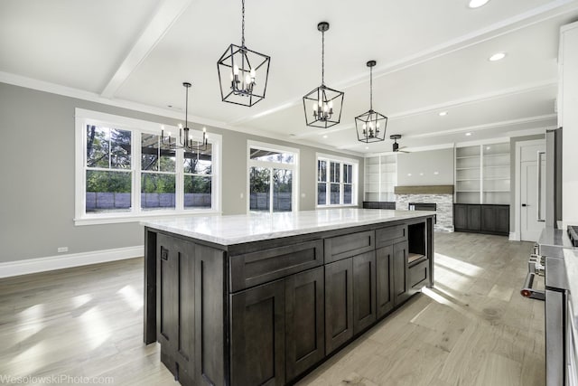 kitchen featuring beam ceiling, a stone fireplace, baseboards, and a wealth of natural light