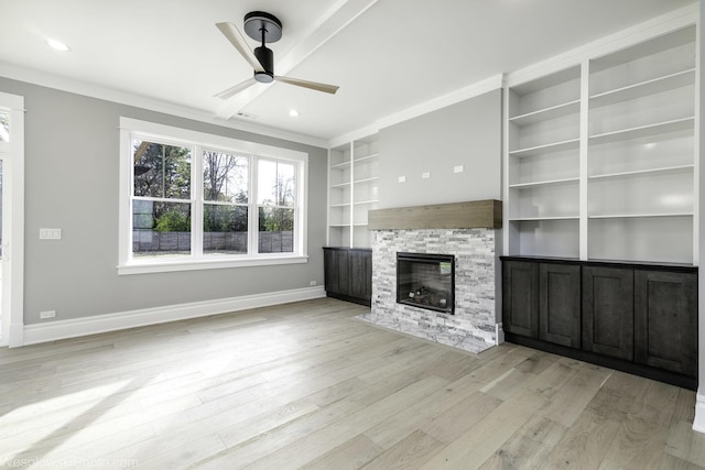 unfurnished living room with baseboards, crown molding, a fireplace, and light wood finished floors