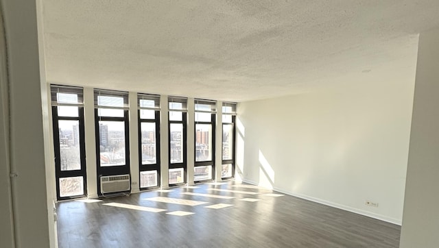 spare room with dark wood finished floors, a textured ceiling, baseboards, and expansive windows