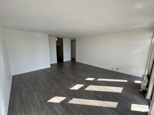 empty room featuring baseboards, dark wood-style flooring, and a textured ceiling