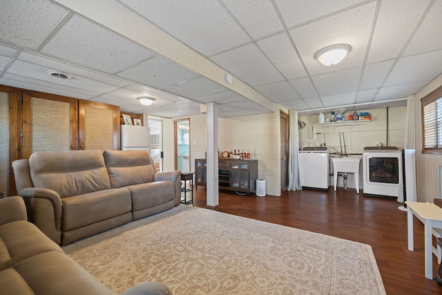 living area featuring a drop ceiling, washer / dryer, wood finished floors, and visible vents