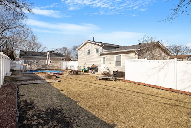 rear view of property with an outbuilding, a patio area, a yard, and a fenced backyard